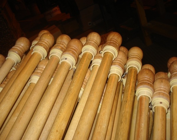 Assorted wooden flag poles with plastic swivels, metal clips, plastic fasteners, screws, and finial tops, available in bulk.